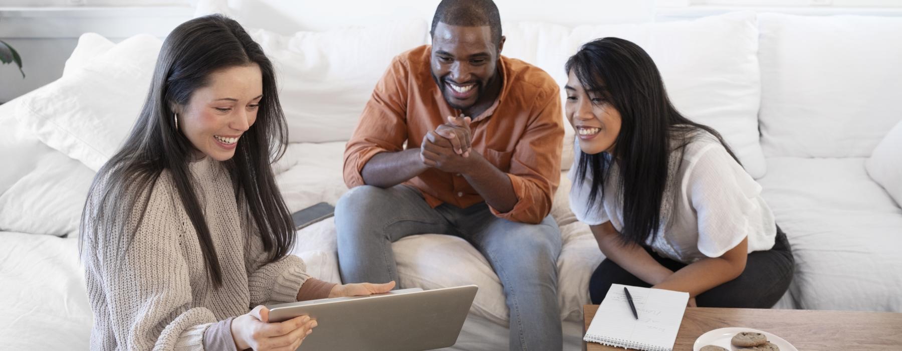 a man and woman sitting on a couch looking at a laptop